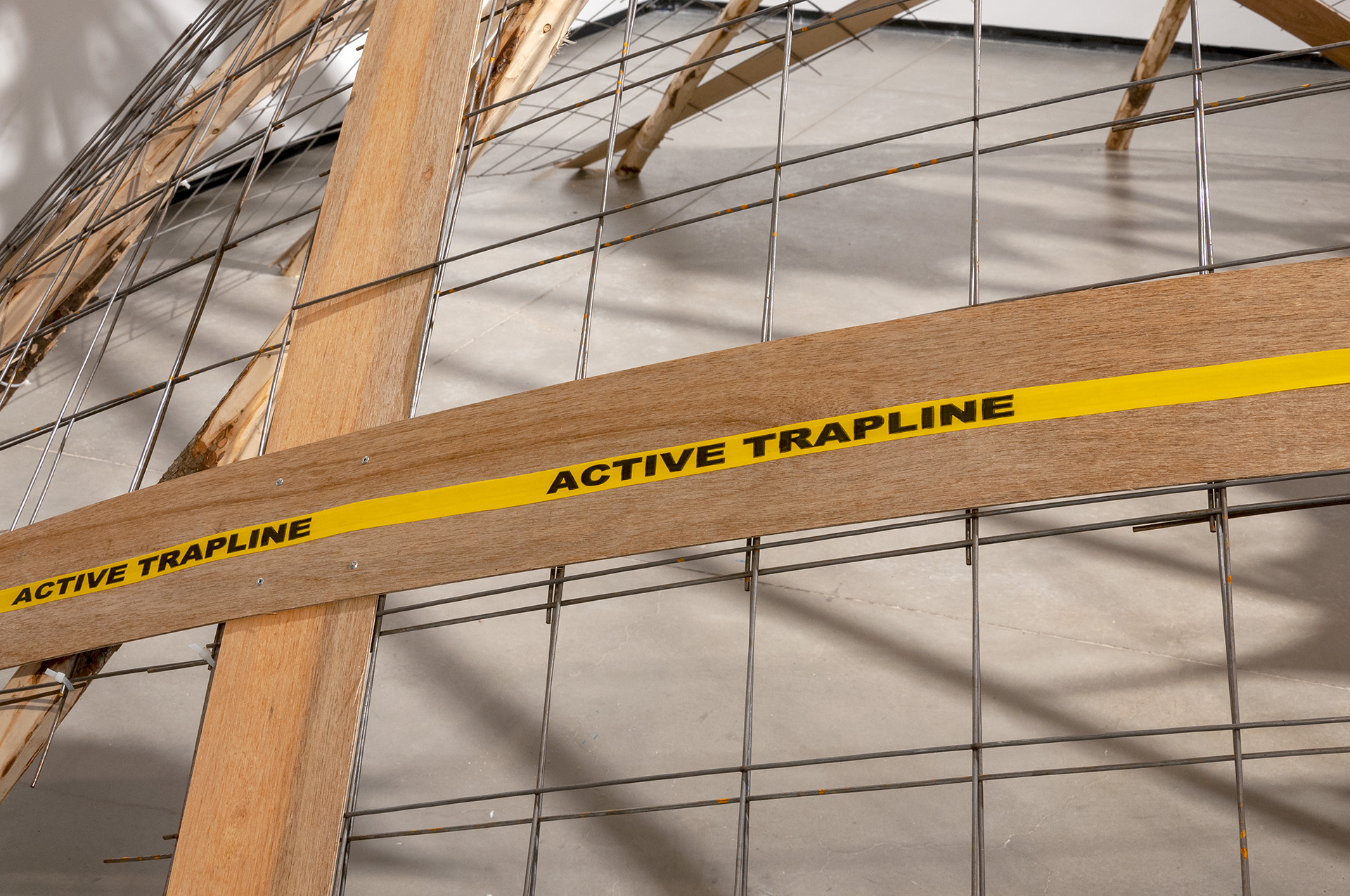 Detail of a wire mesh structure with wooden crossbeams with a band of “Active trapline” text