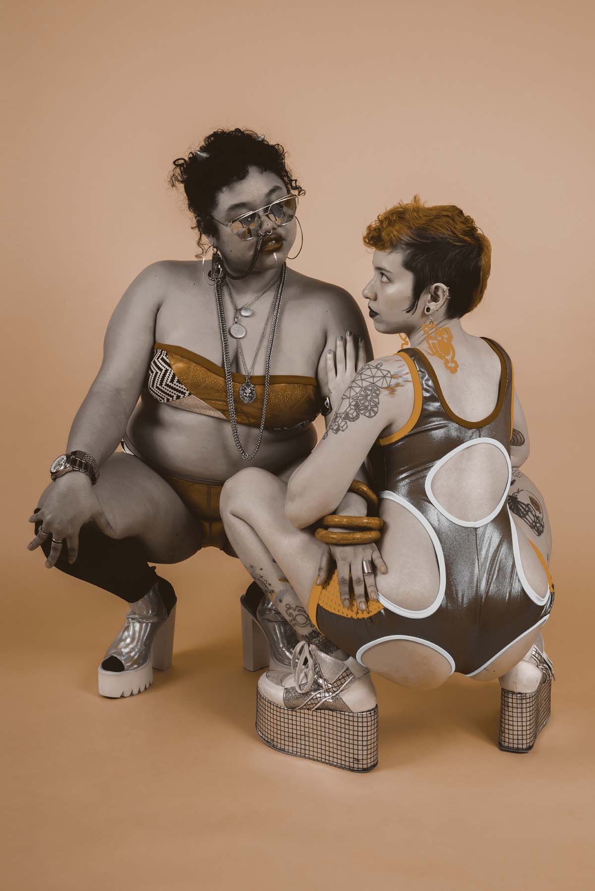 Sepia image of two people posing in front of a backdrop wearing spandex clothing by Rebirth Garments